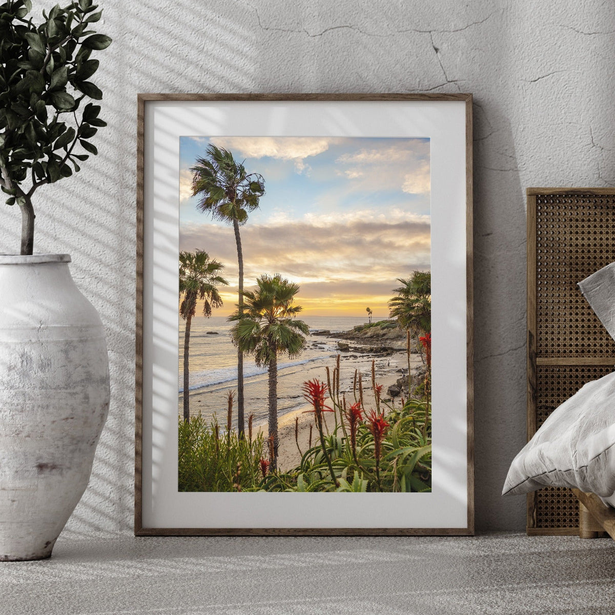 Laguna Beach photography displayed above a bed in a neutral room
