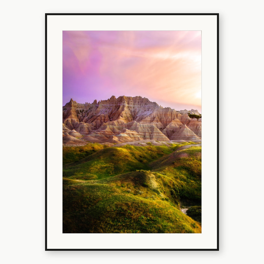 South Dakota Badlands ridges, green hills and a pink sky, shown as a print with a white mat and thin black frame.