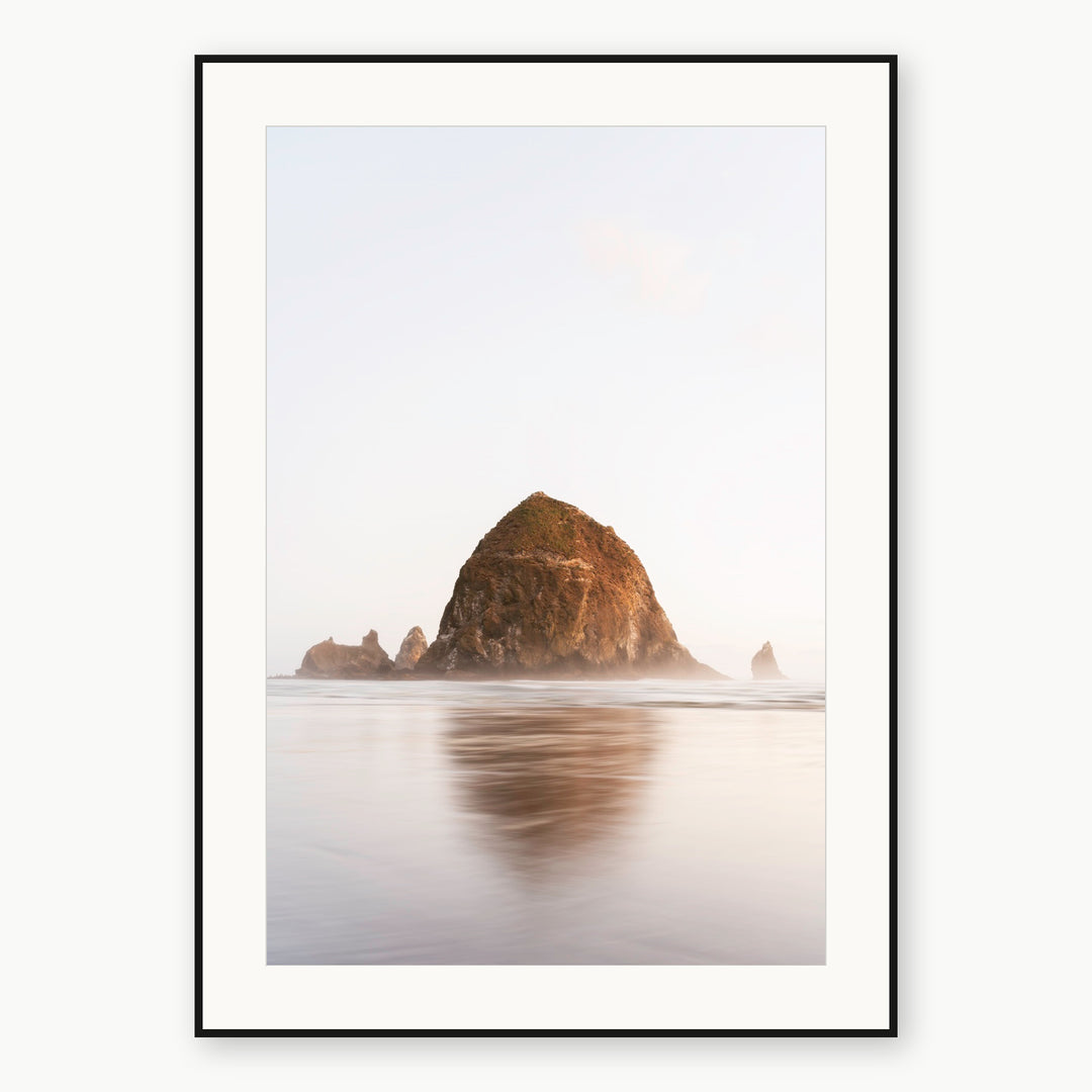 Haystack Rock reflected at Cannon Beach, Oregon, shown as a print with a white mat and thin black frame.